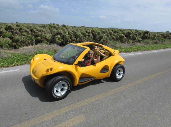 Yellow dune buggy driving along scenic coastal road Cozumel