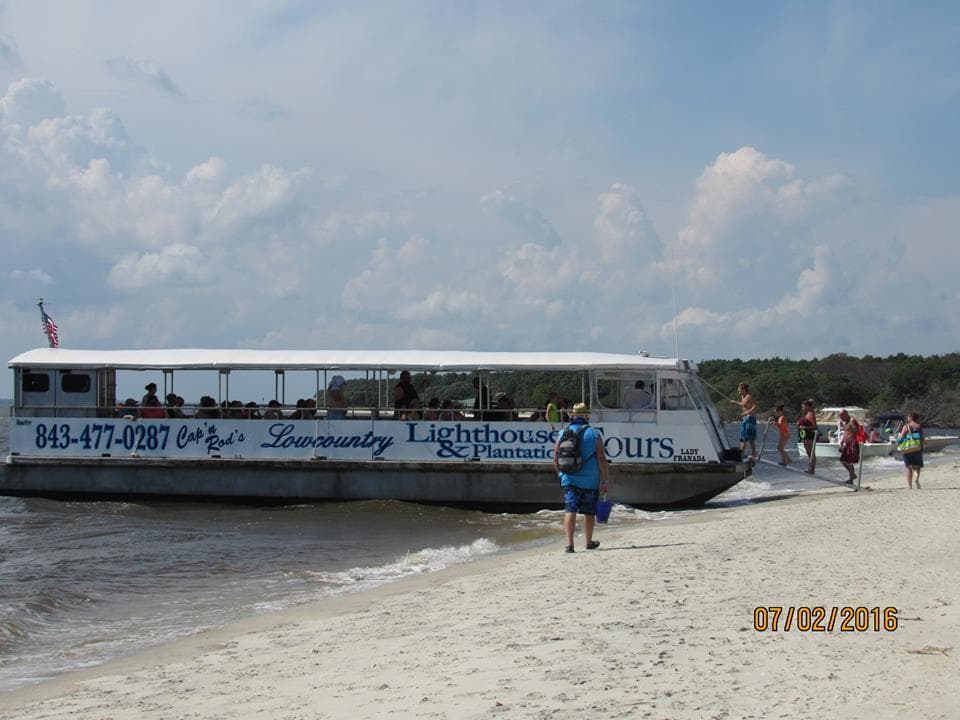 Beach landing boat tour with passengers boarding on sandy shore
