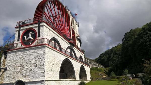 Large historic waterwheel at hillside, industrial heritage site visit