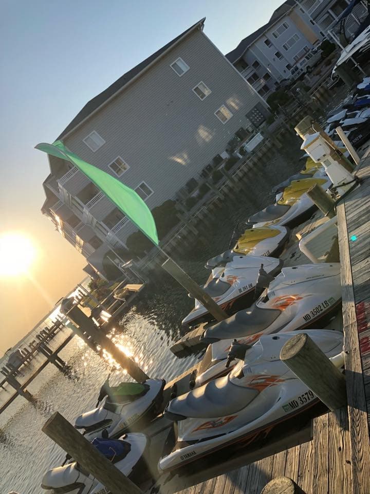 Sunset-lit dock with multiple jet skis and waterfront condos
