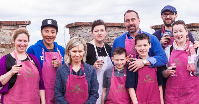 Group cooking participants on seaside terrace holding drinks