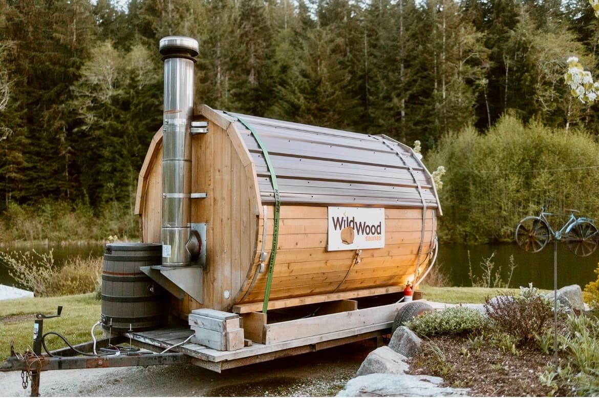 Barrel sauna beside a forest lake on trailer, lakeside soak