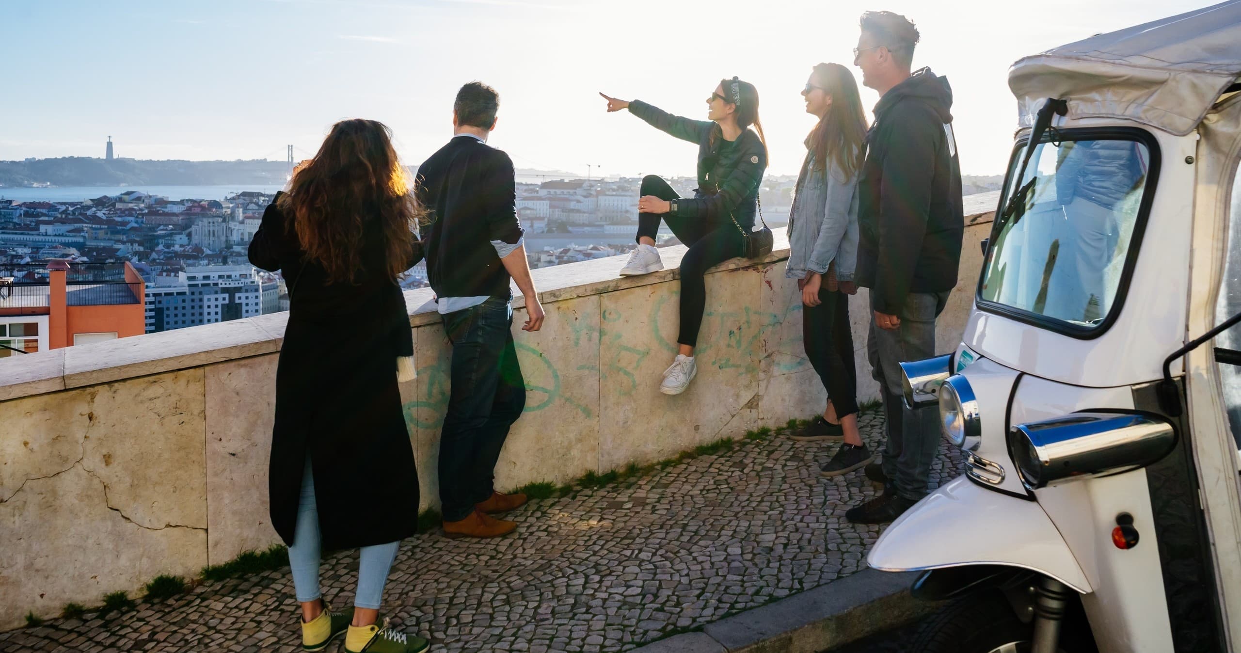 Friends overlooking Lisbon cityscape from viewpoint at sunset