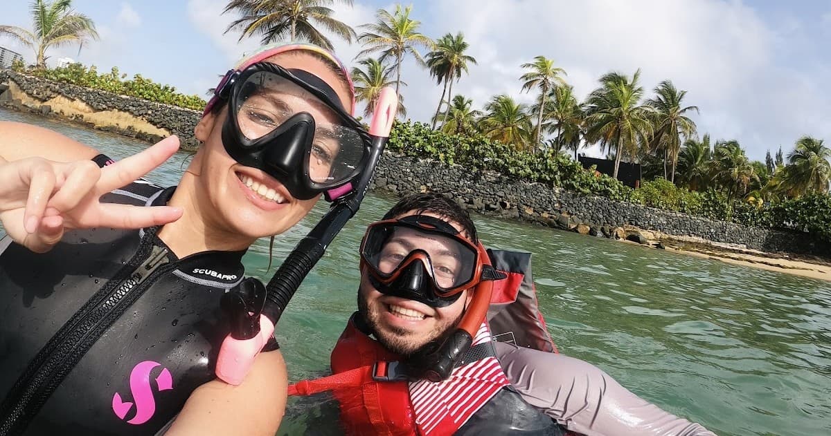 Smiling snorkelers posing near palm-lined shore in tropical bay