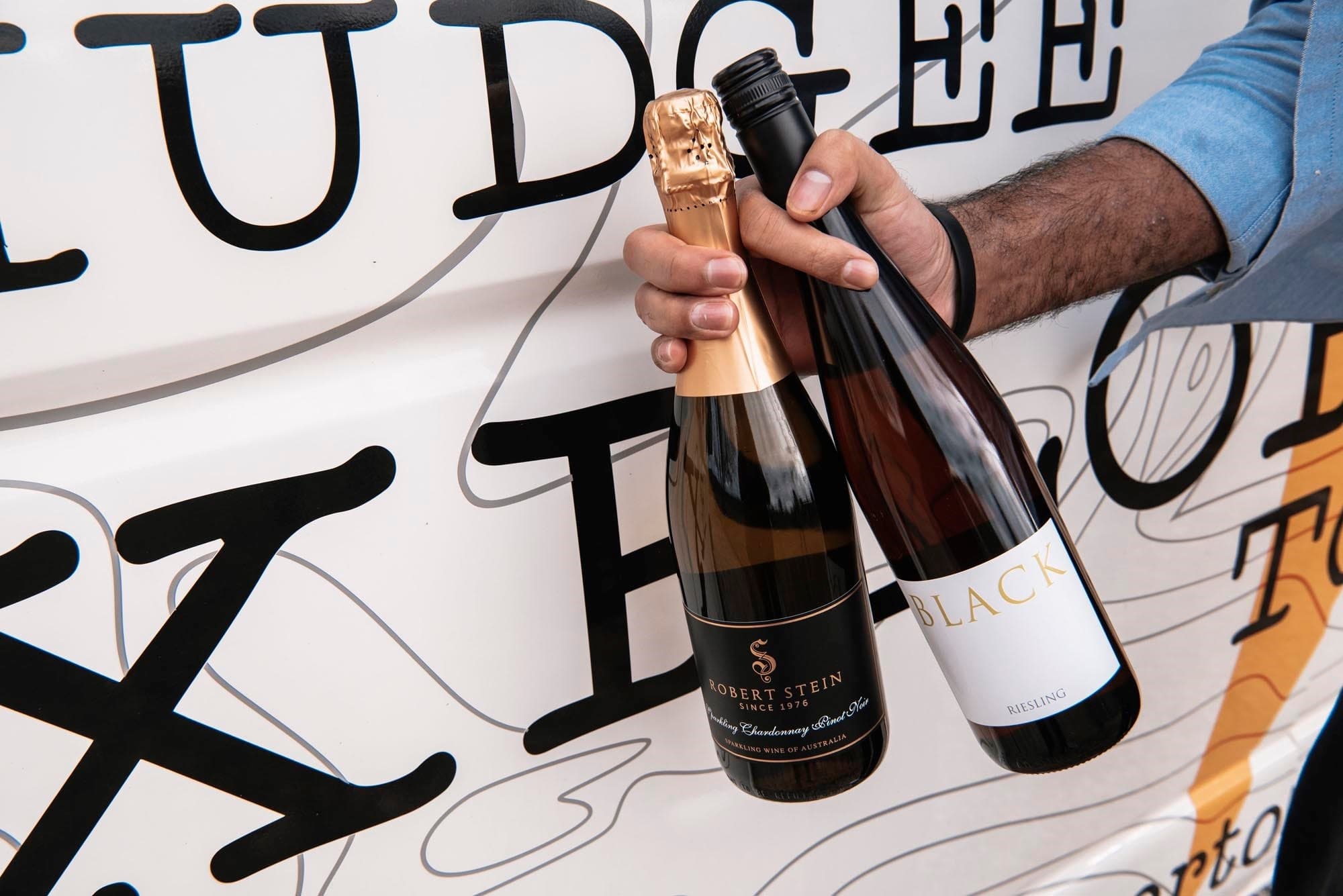 Close-up of sparkling wine bottles beside Mudgee Explorer tour van