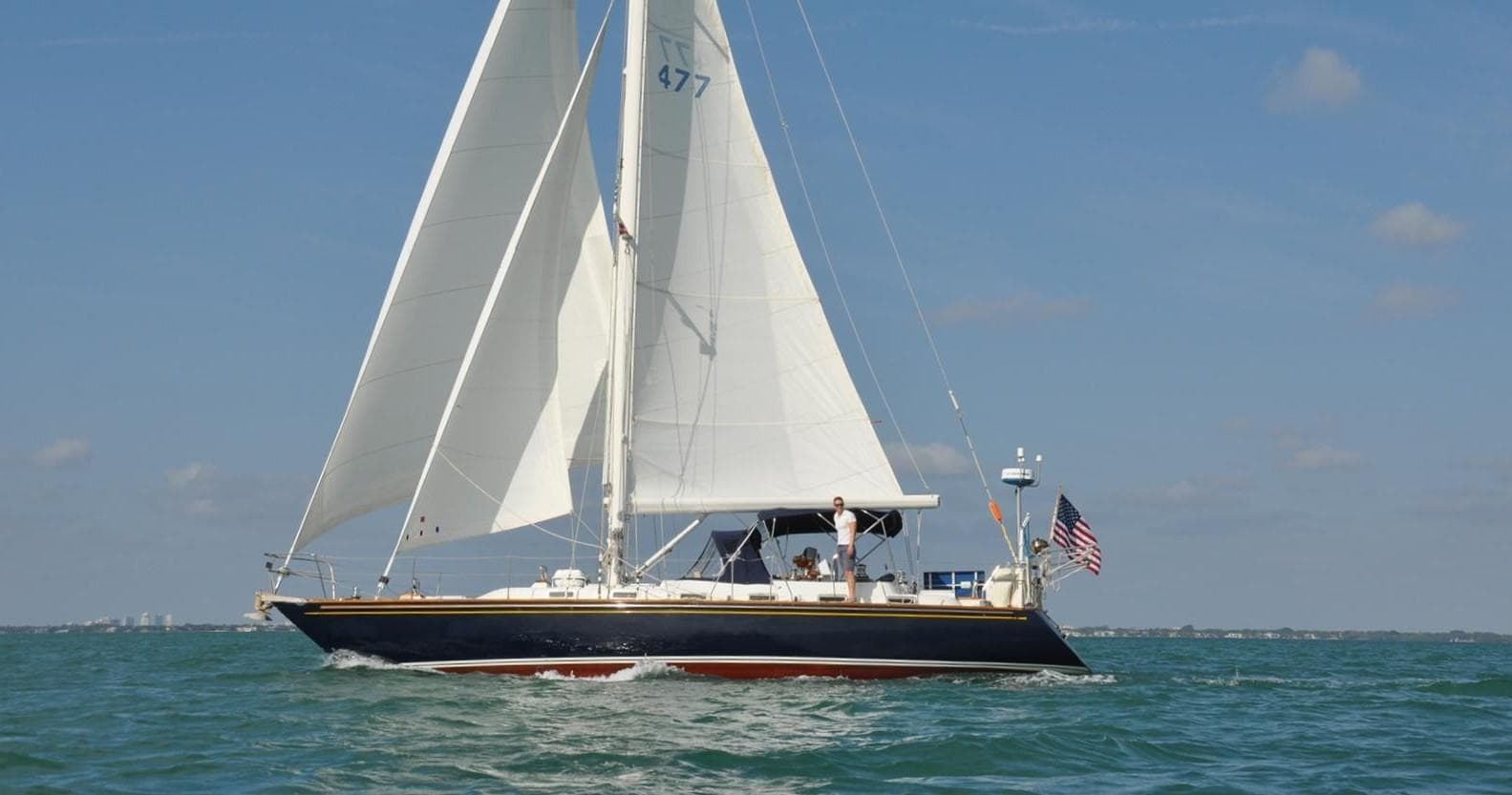 Sailing yacht cruising coastal waters under clear blue sky