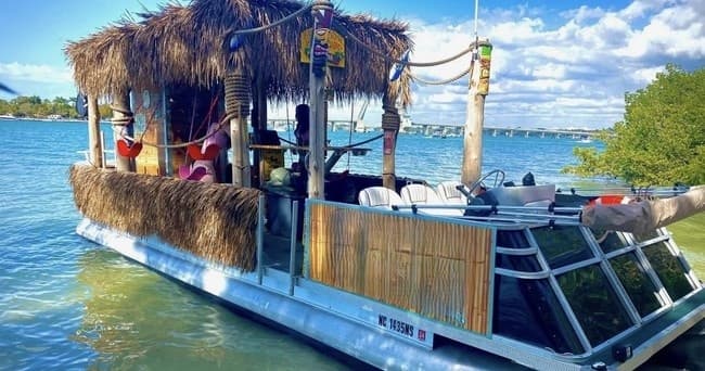 Tiki boat cruising tropical bay with passengers on deck
