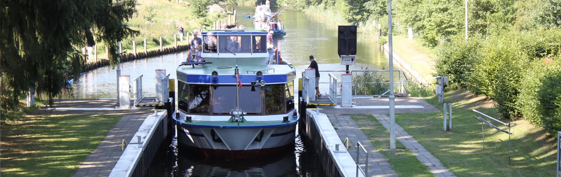 Canal boat in lock with passengers on riverside mooring