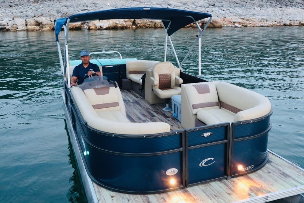 Blue pontoon boat docked on calm lake at sunset, scenic view