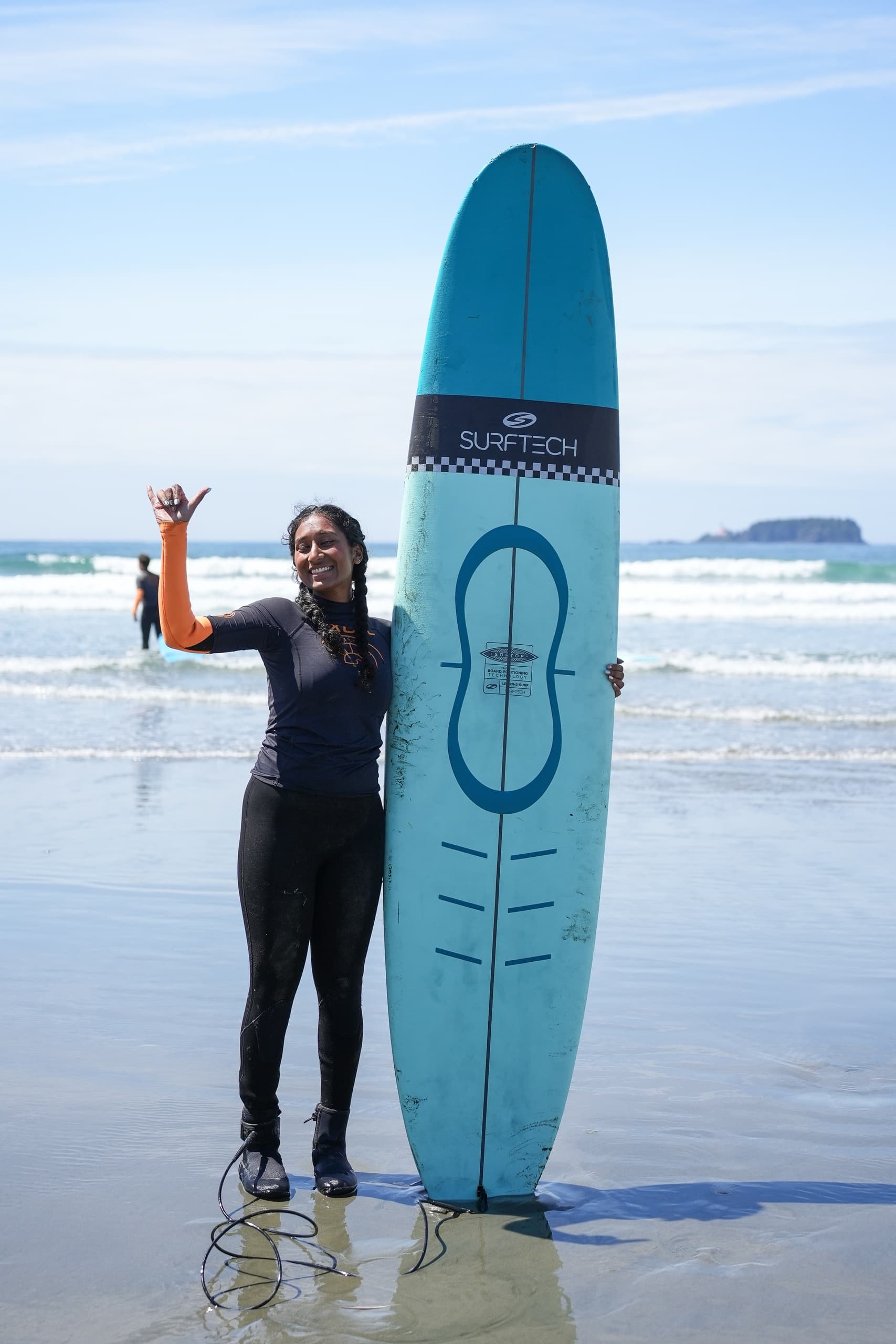 Surfer holding blue board on wet sand with ocean waves