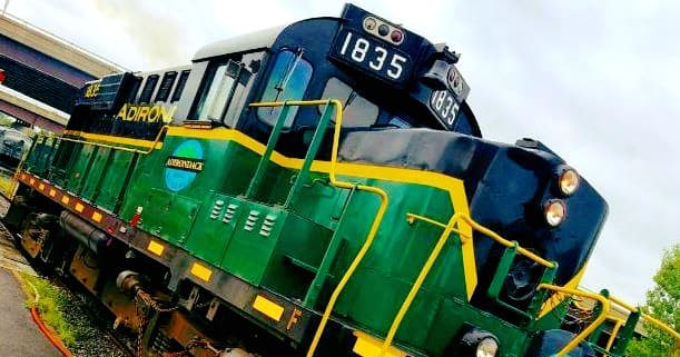 Vintage green locomotive parked on scenic rail siding at depot