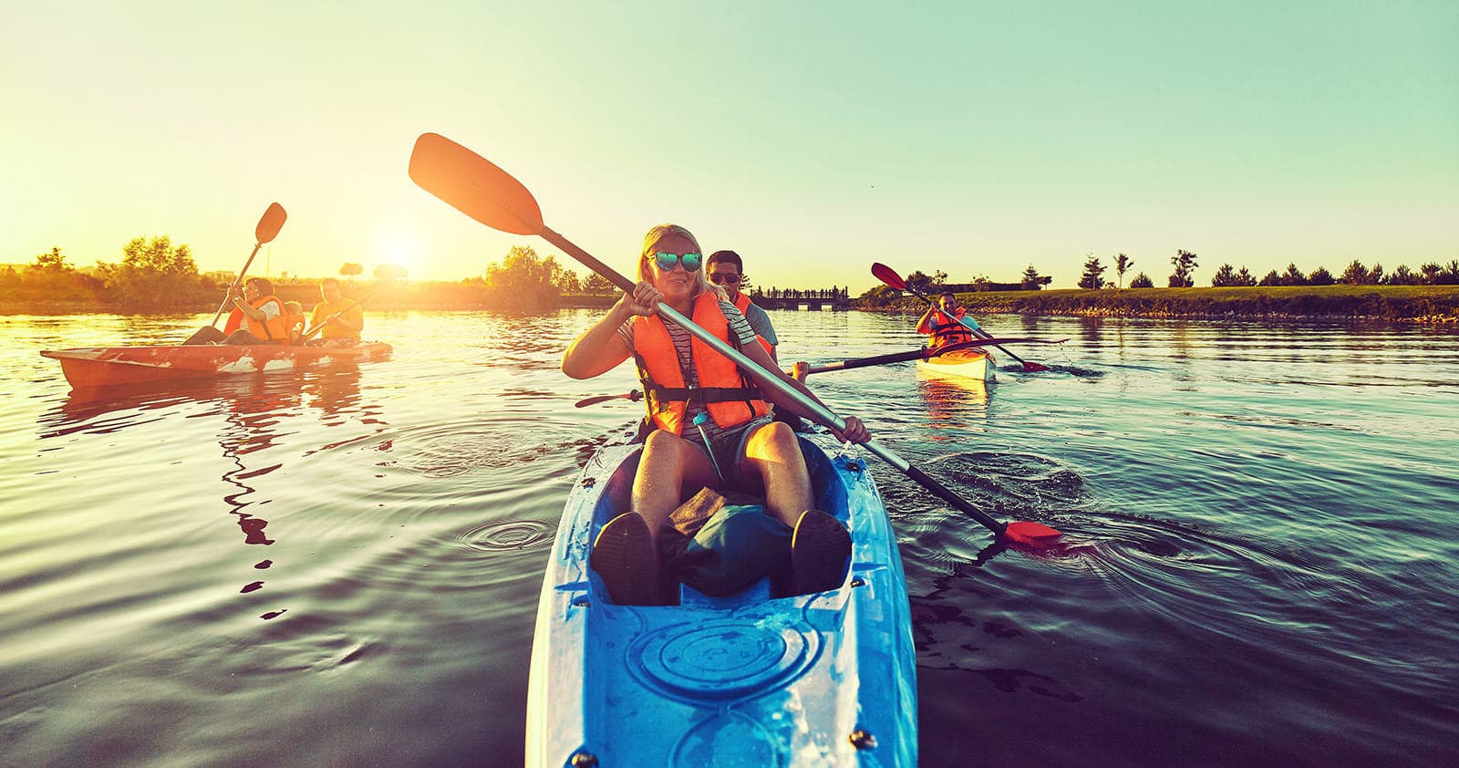 Kayakers paddling at sunset across calm coastal waters