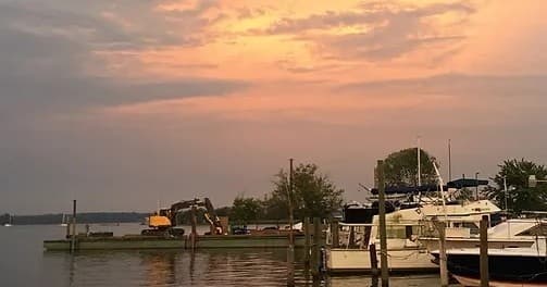Sunset over DC marina with sailboats on calm river waterfront