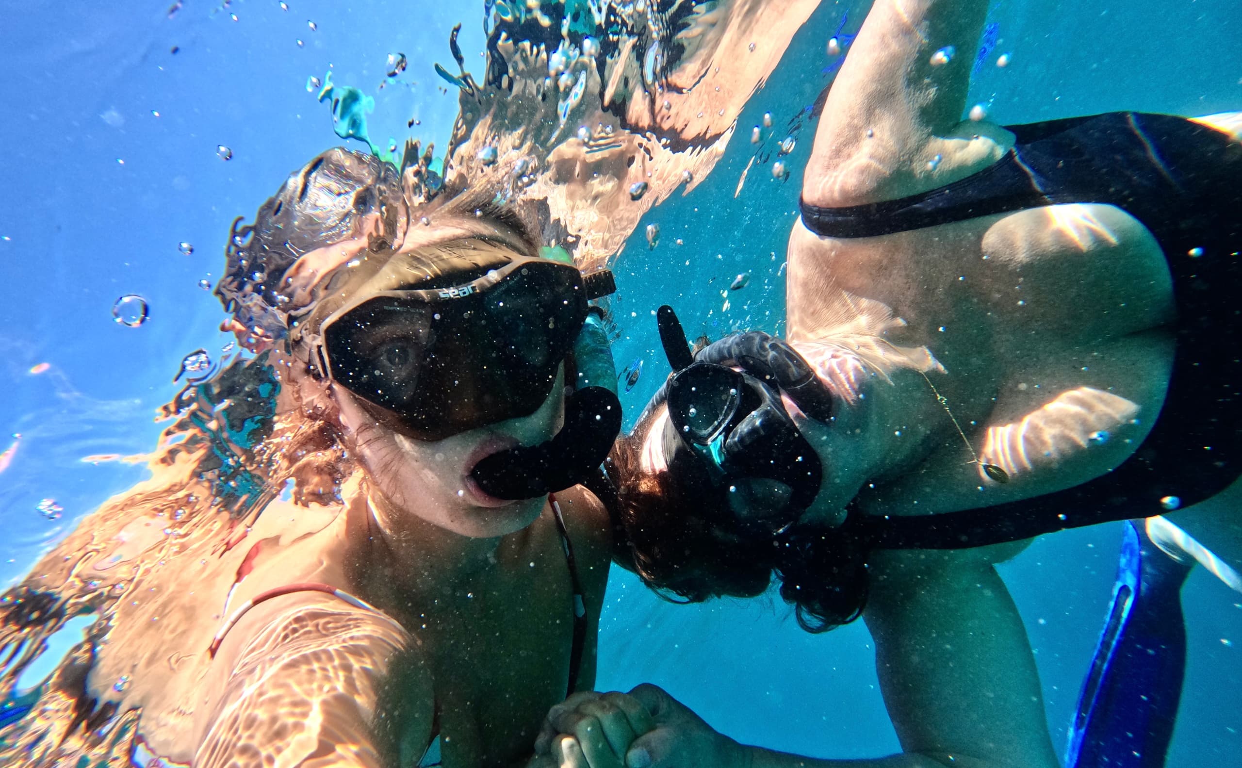Underwater snorkeling selfie of two people in tropical blue water