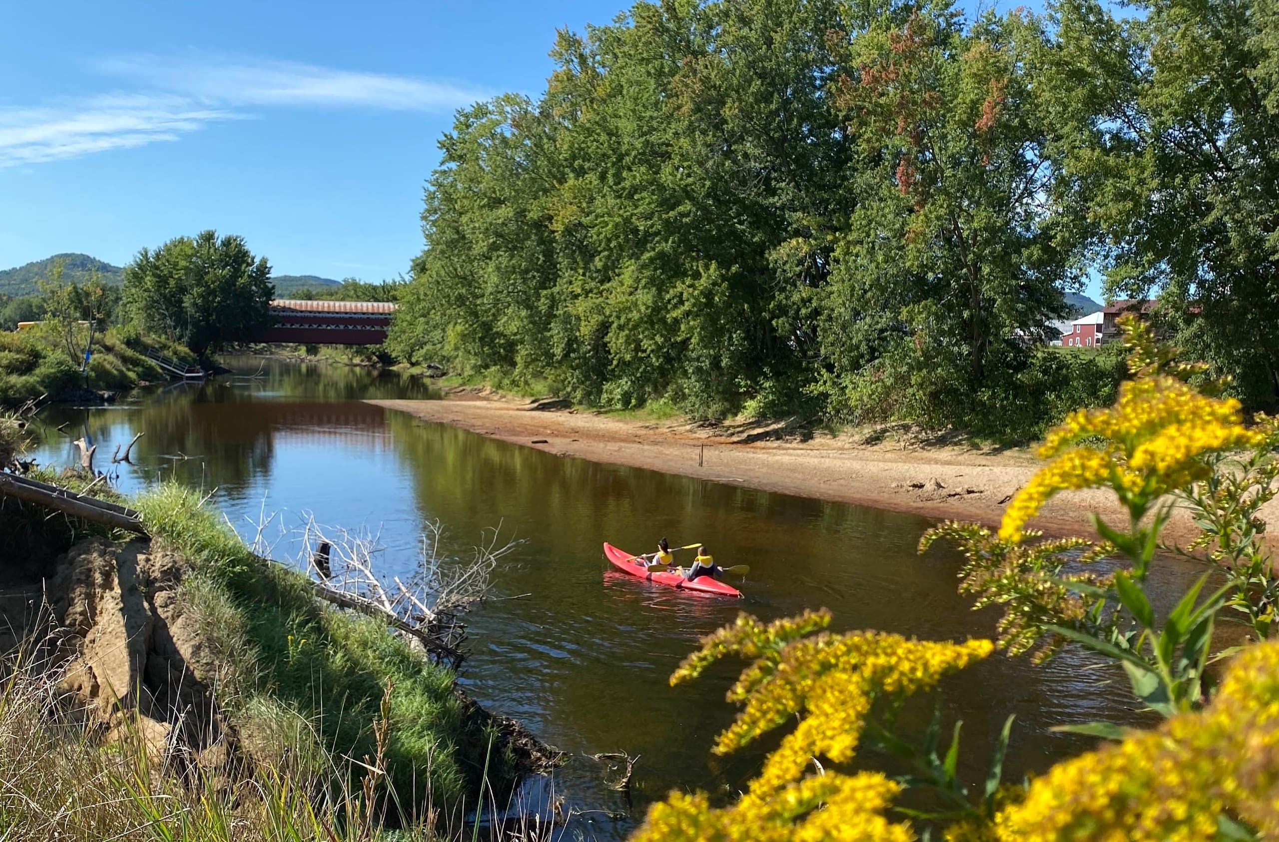 Kayaker paddling red kayak on calm scenic river with forested banks
