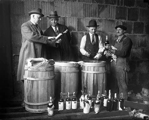 Vintage workers inspecting liquor barrels in indoor distillery