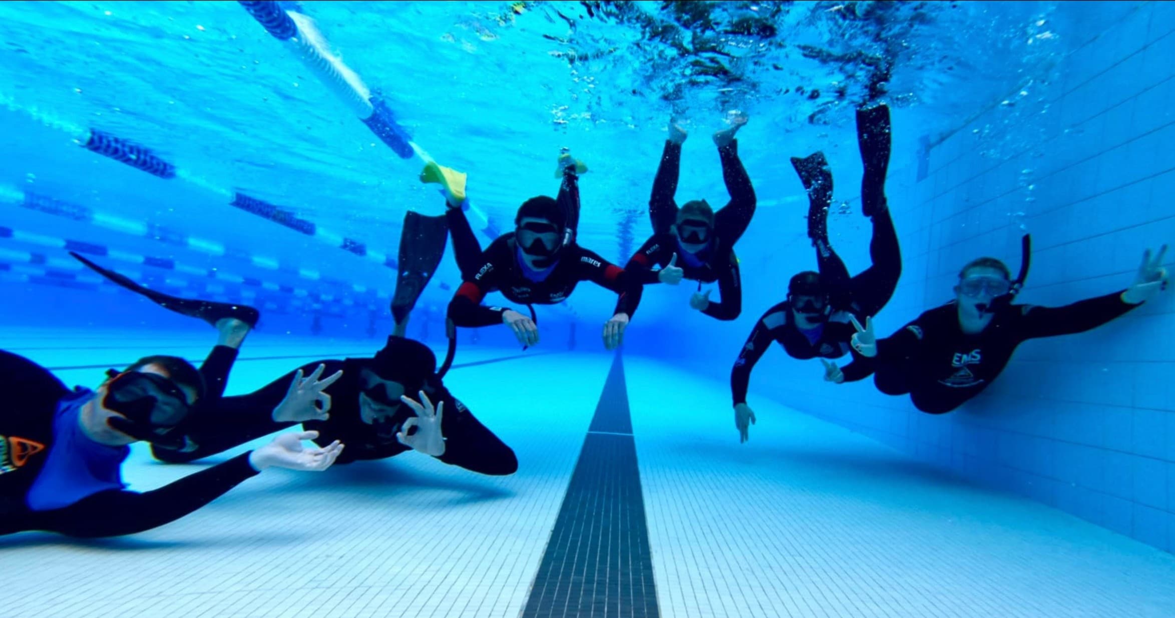 Freediving group underwater in clear pool training session
