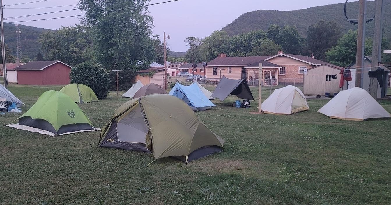 Backpackers camping in grassy field at shared campsite