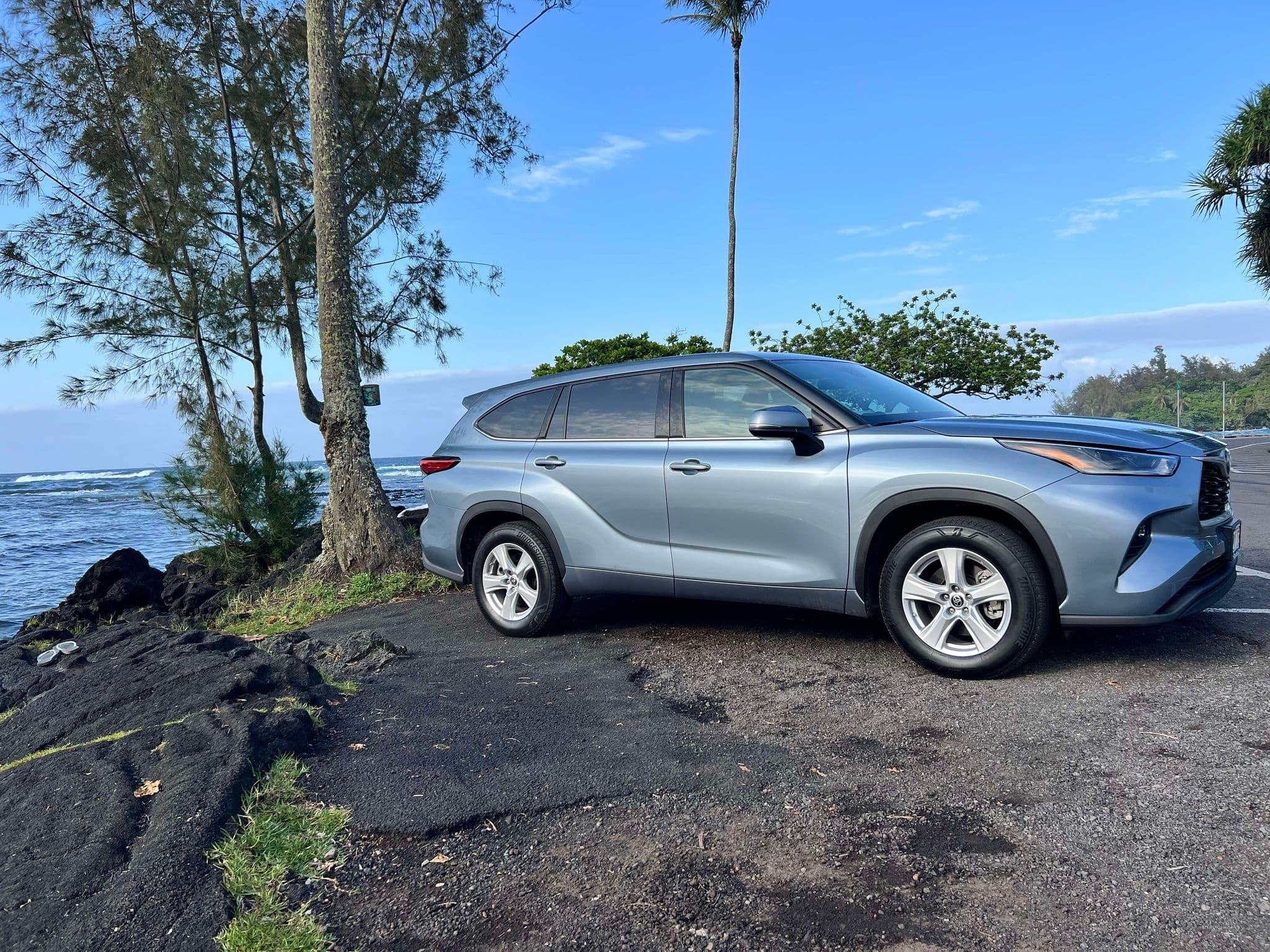 SUV parked on volcanic shoreline with ocean view in Hawaii
