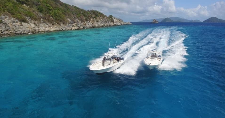 Two powerboats racing along turquoise Caribbean coast, aerial