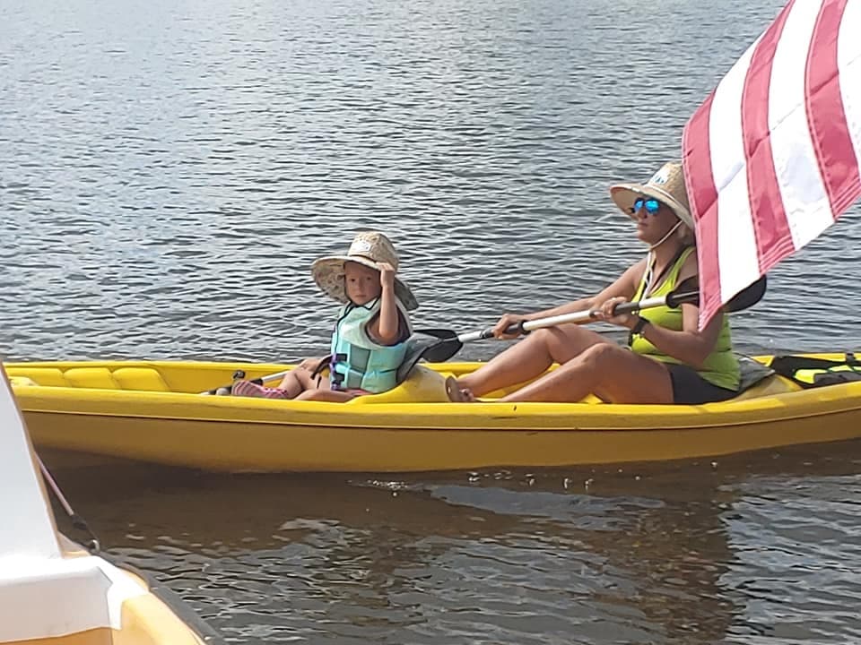 Two kayakers paddling a yellow tandem kayak with flag