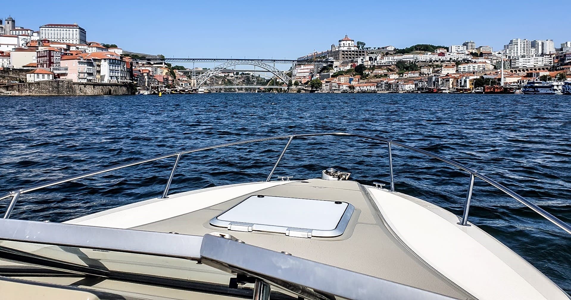 Boat bow cruising toward Porto waterfront skyline, river tour