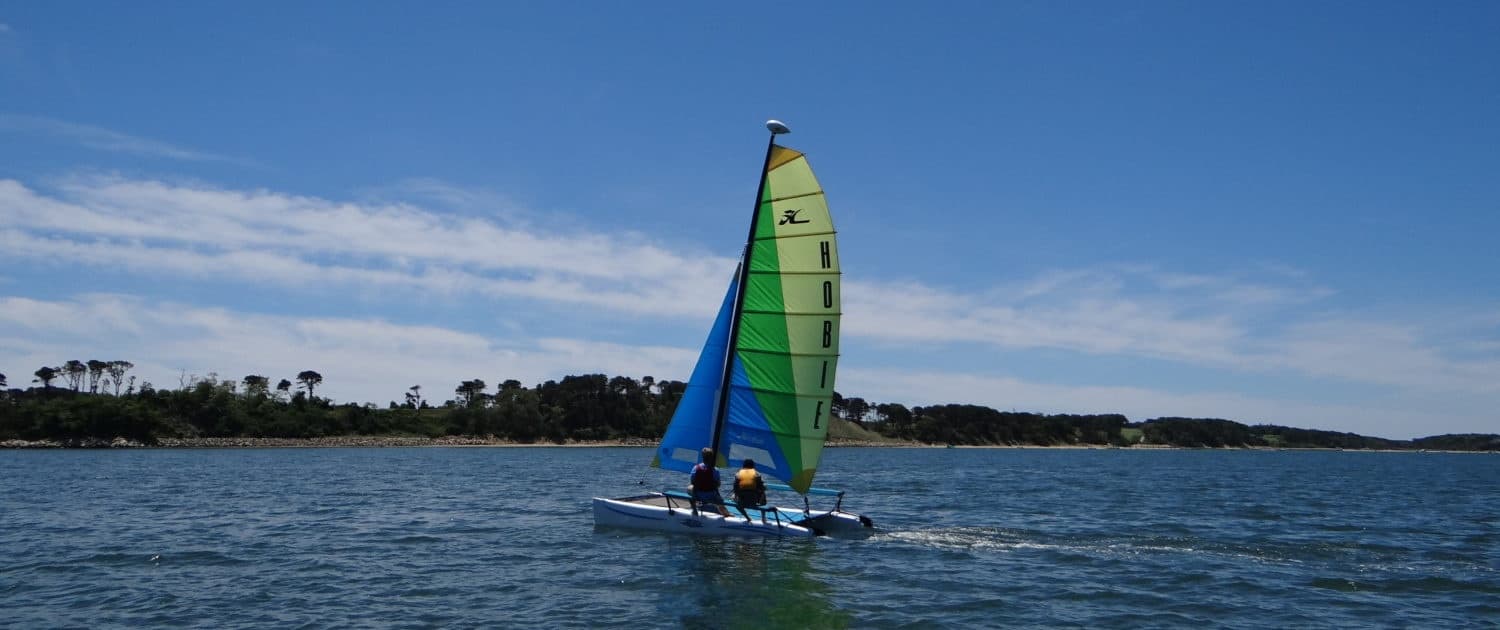 Small sailboat with colorful sail on open coastal waters