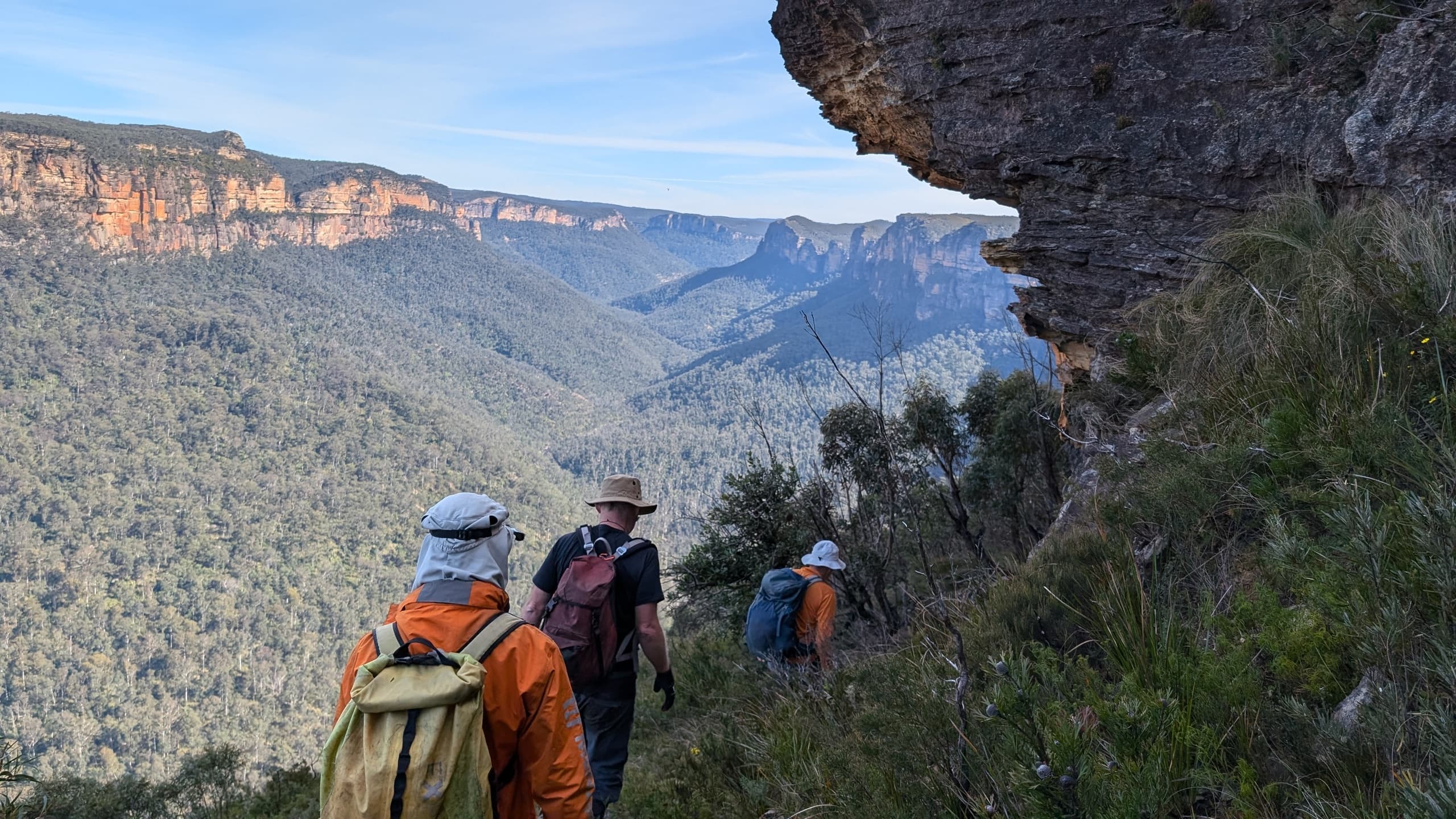 Hikers trekking cliff edge with panoramic valley views