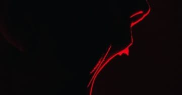 Dramatic red-lit profile portrait of person in low light