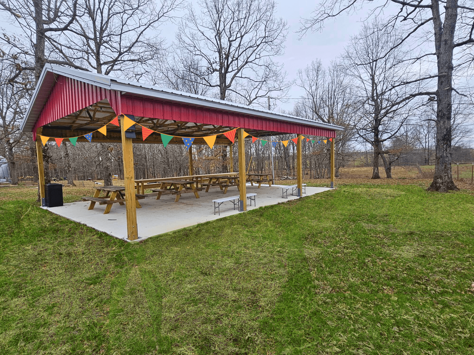 Open-air picnic pavilion with bunting on grassy farm field