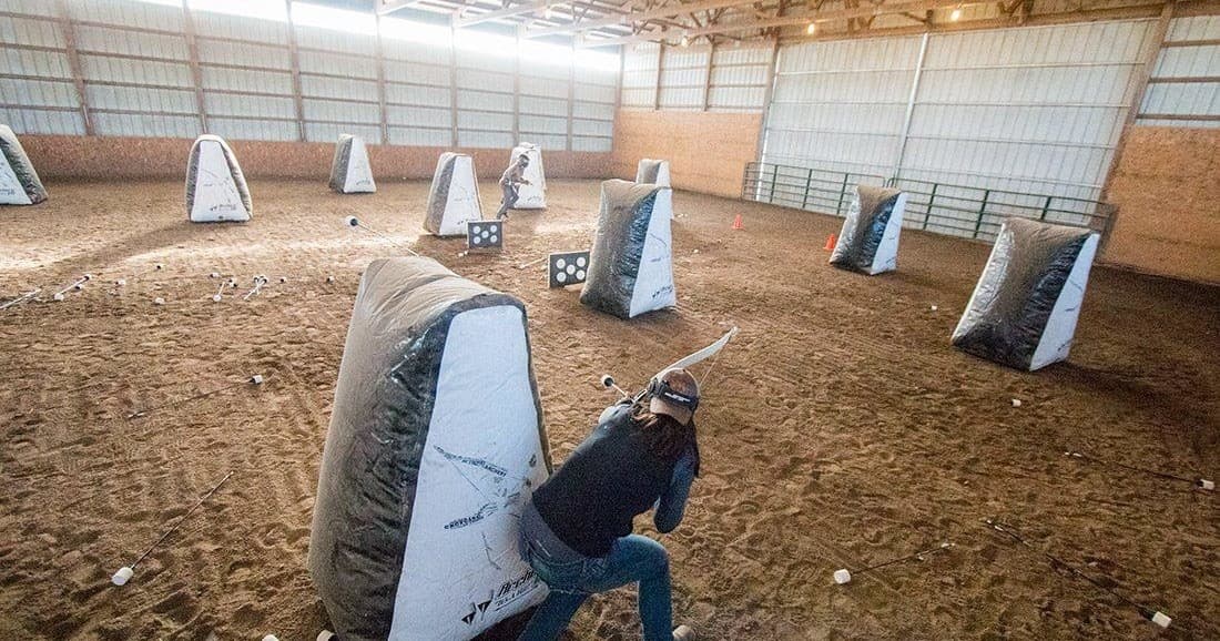 Indoor archery arena with players behind inflatable bunkers