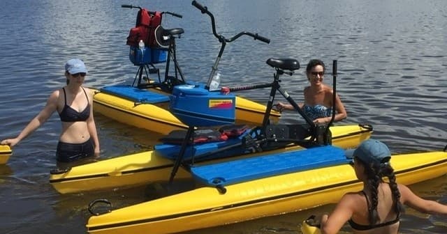 People on pedal kayaks and water bikes exploring calm lake waters