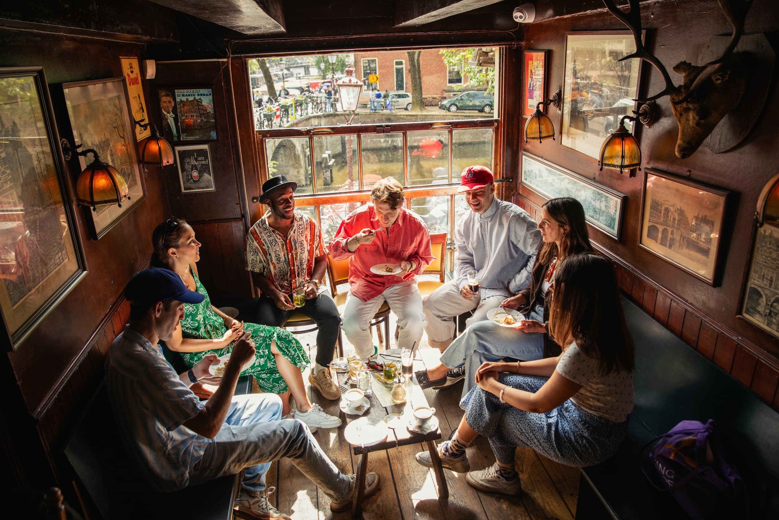 Group socializing inside cozy Amsterdam canal boat cabin