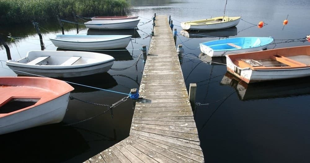 Rowboats moored at wooden dock on calm lake, scenic waterfront