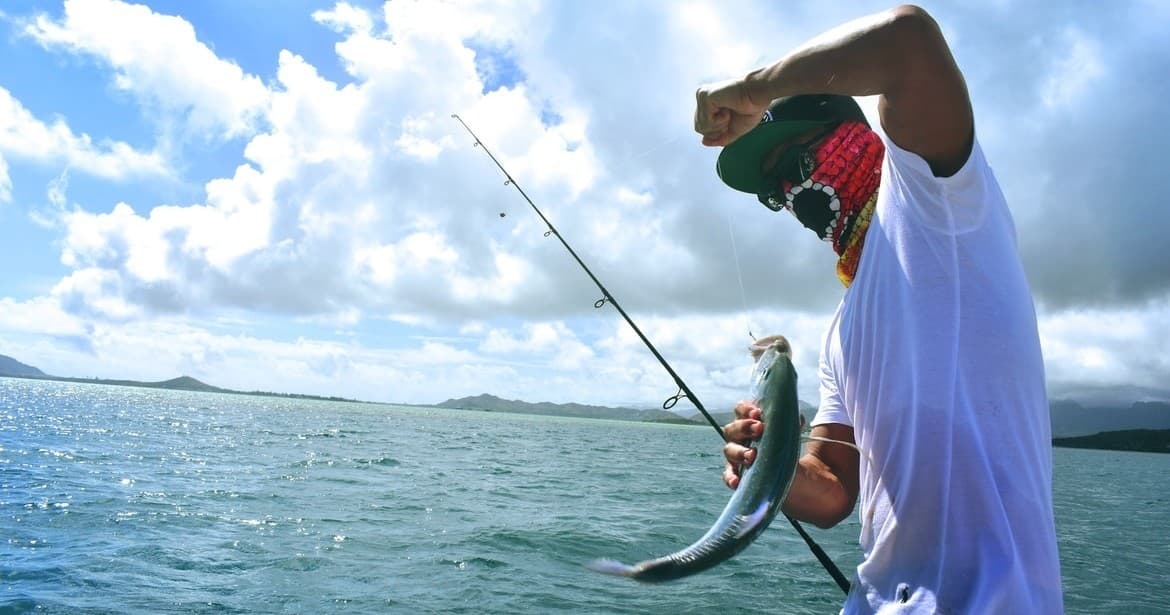 Angler reeling in fish from tropical sea during fishing trip