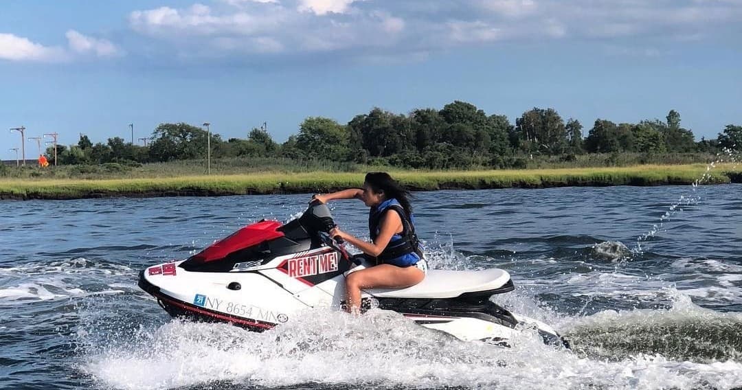 Solo rider on jet ski skimming coastal inlet waters, summer