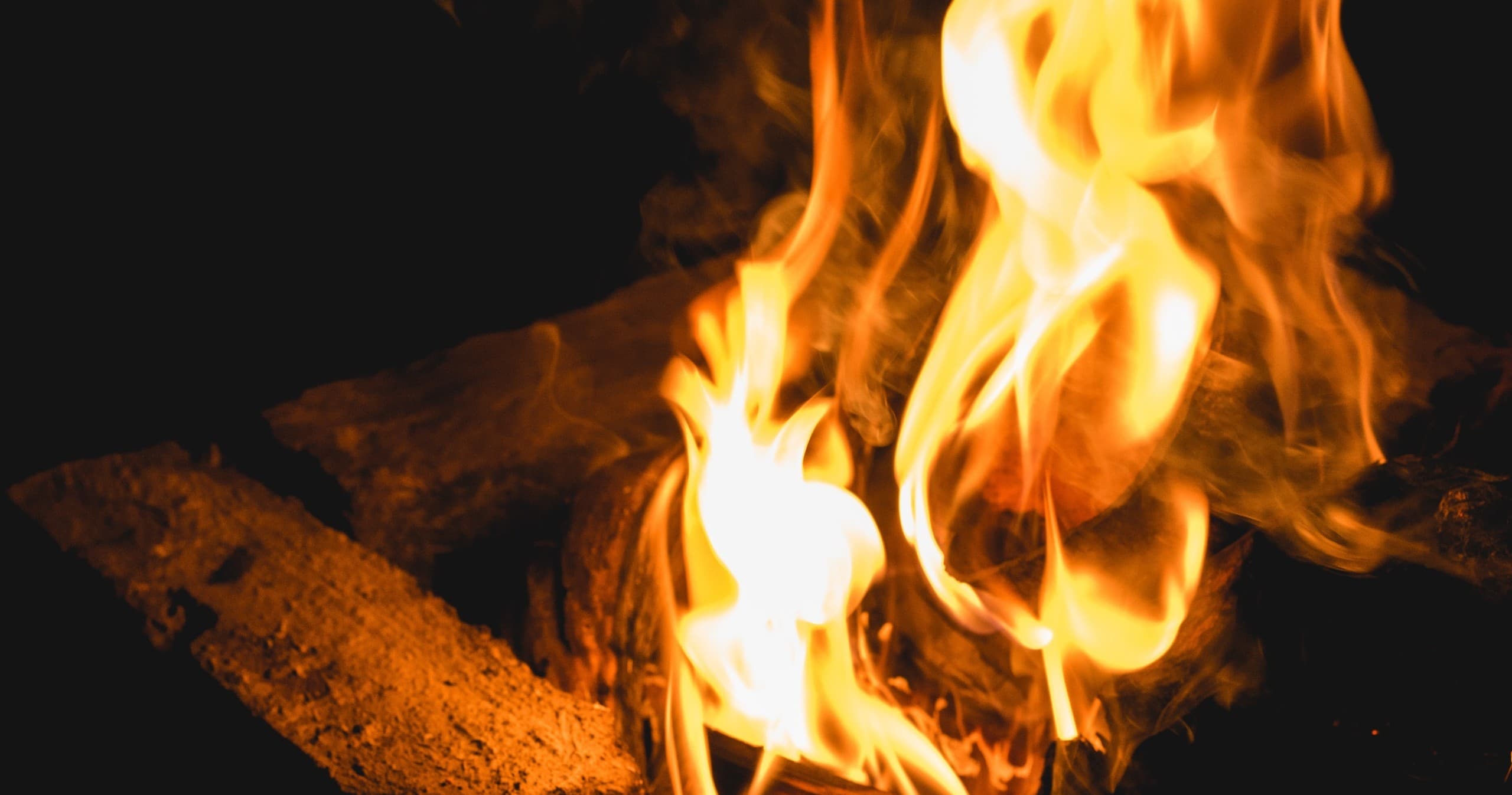 Close-up campfire flames on logs for outdoor firepit gathering