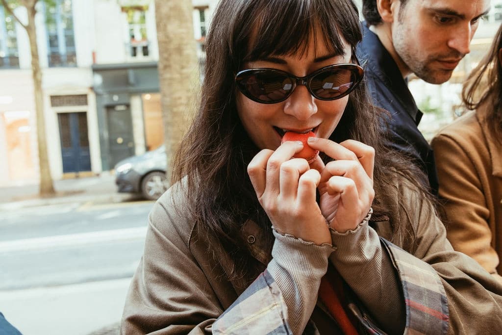 Woman sampling street food outdoors on Paris walking food tour