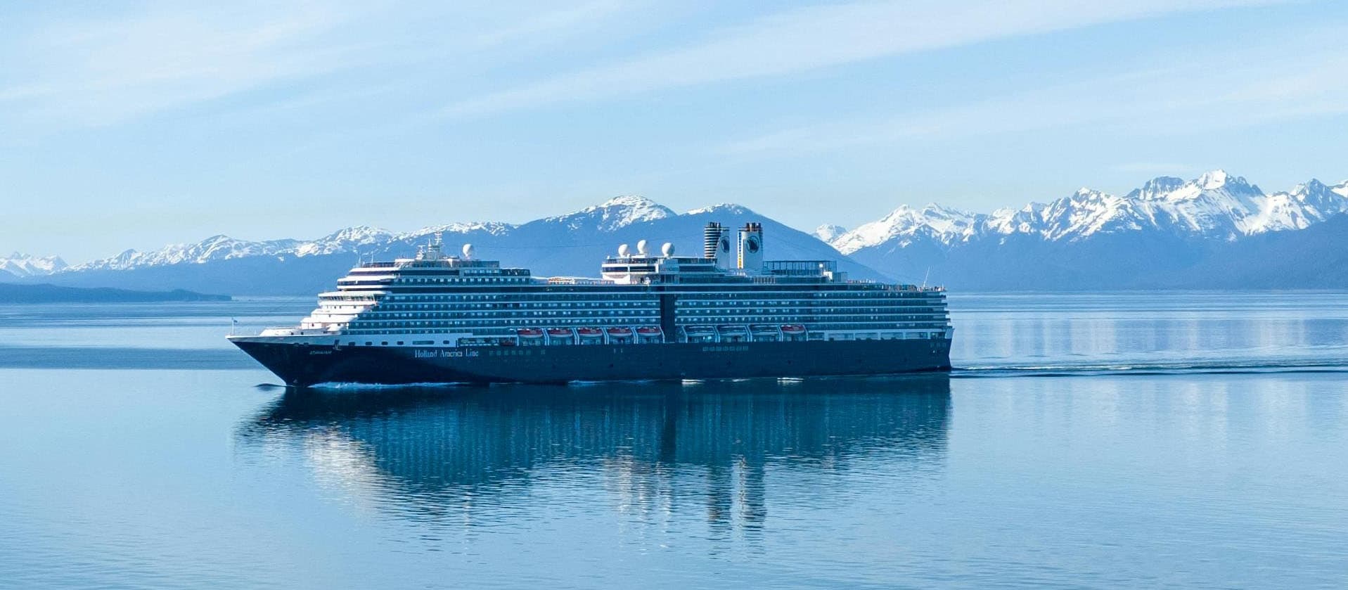 Cruise ship cruising past snow-capped Alaskan mountains