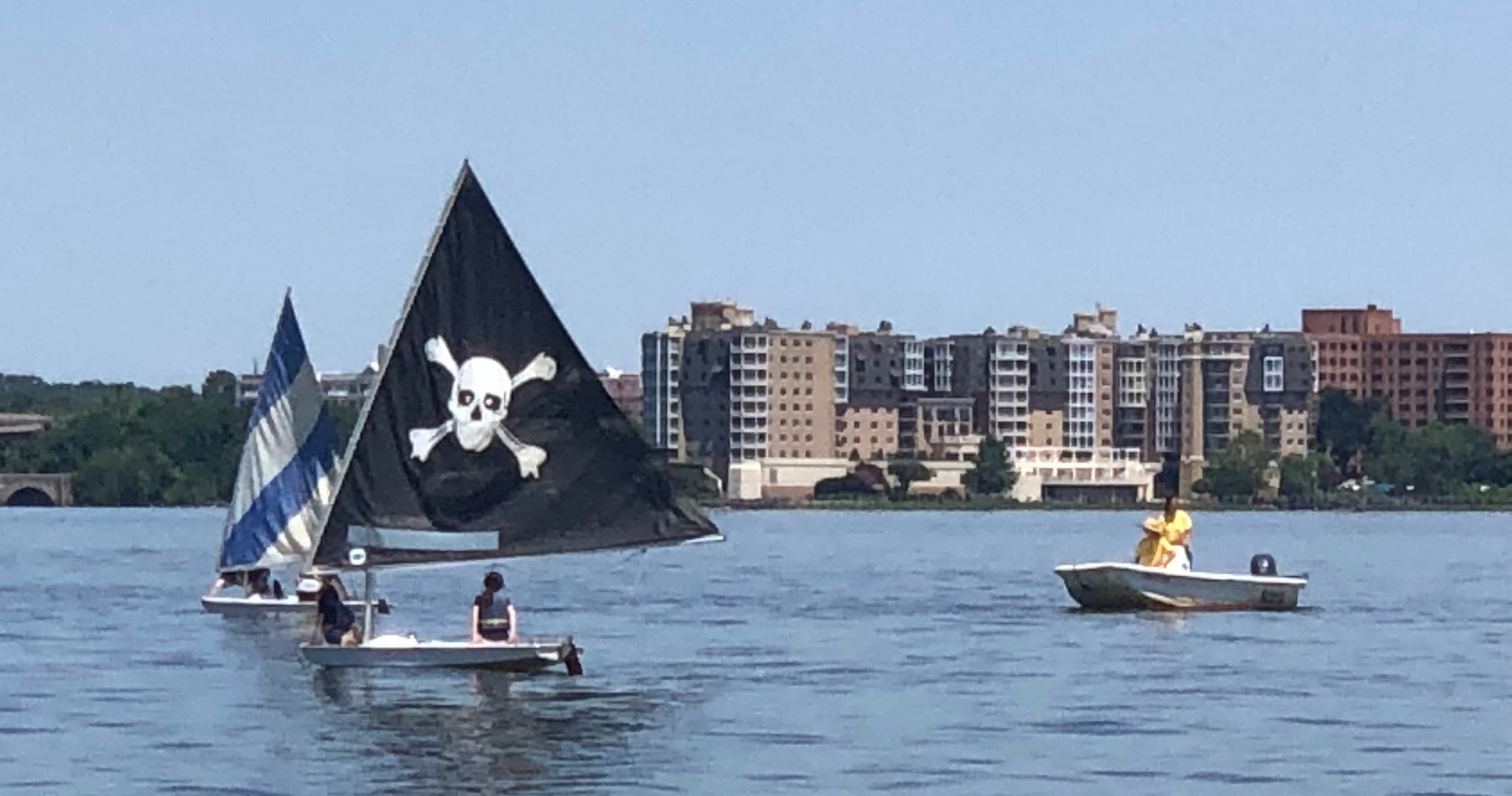 Pirate-flagged sailboat and support boats on Potomac River