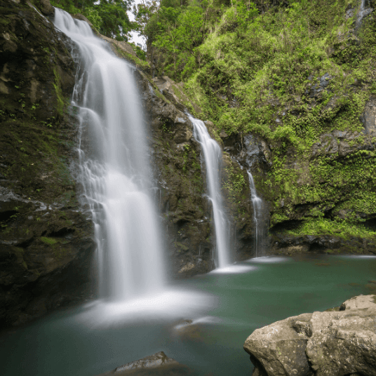 Lush twin waterfalls cascading into tropical pool in Maui