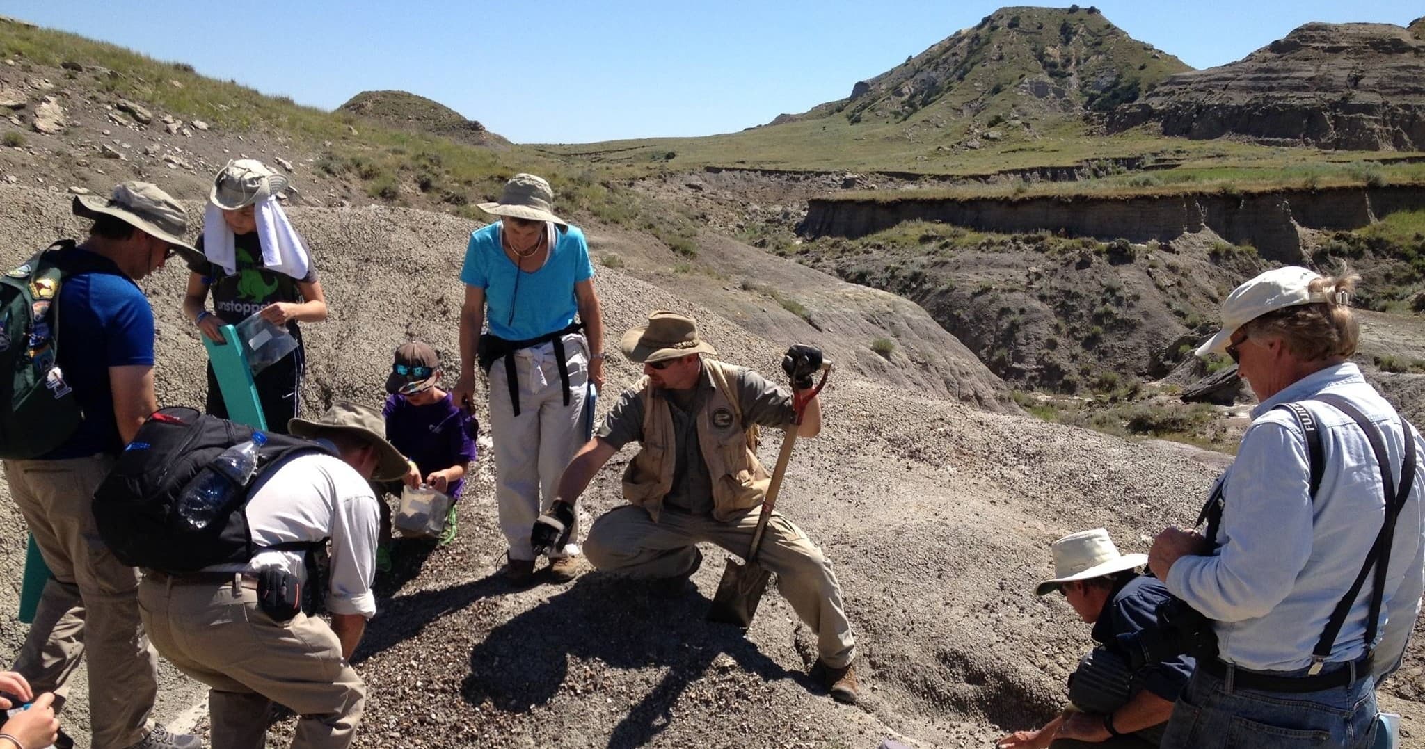 Field team excavating fossils on rocky badlands outcrop