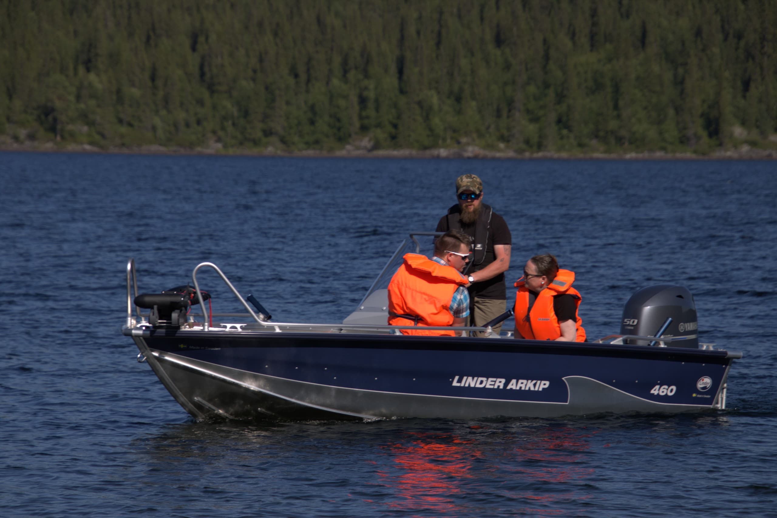Fishing boat with crew wearing life jackets on calm lake