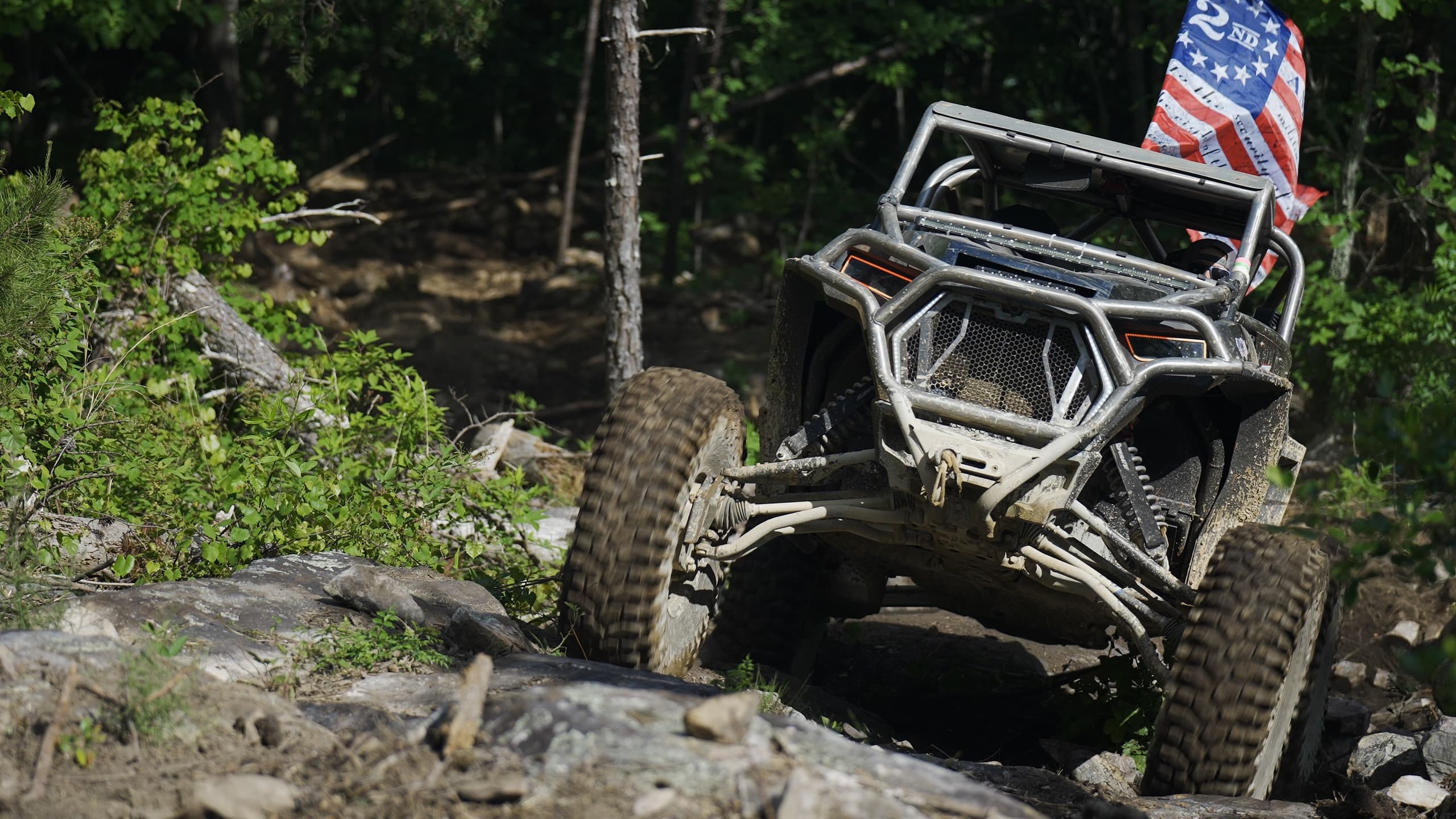 Rock crawler UTV navigating rocky forest trail in off-road action
