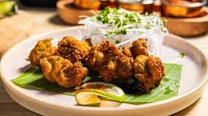 Crispy fried bites served with lime and salad on plate
