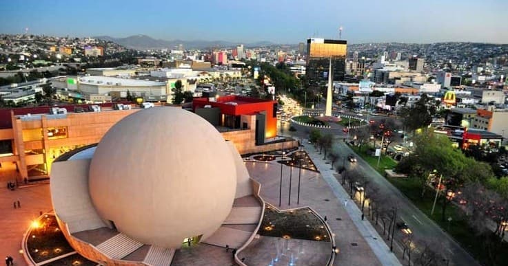 Urban skyline with spherical cultural center at dusk in coastal city