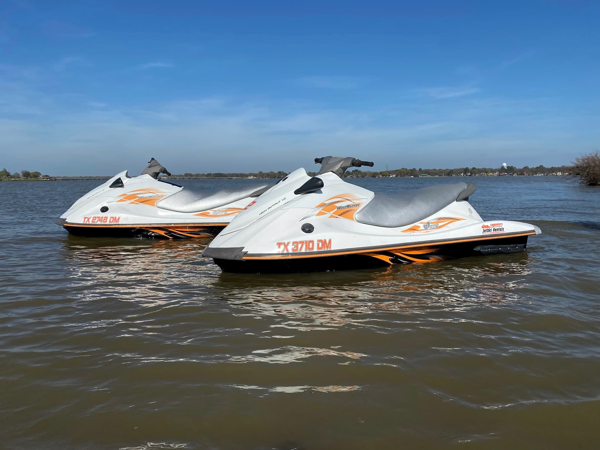 Two jet skis on open lake water under blue sky for rental fun