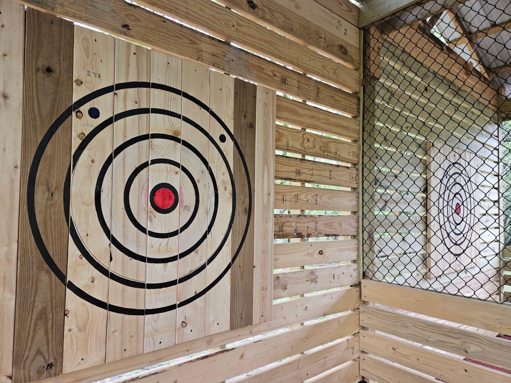 Wooden axe-throwing target lane with safety net at farm