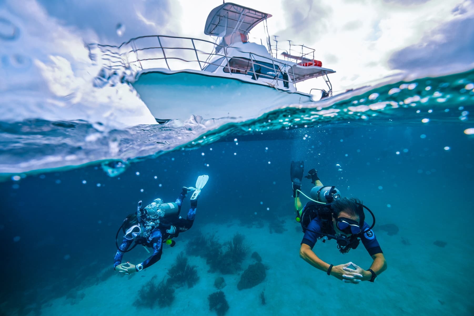 Boat and scuba divers captured half-above half-below ocean scene