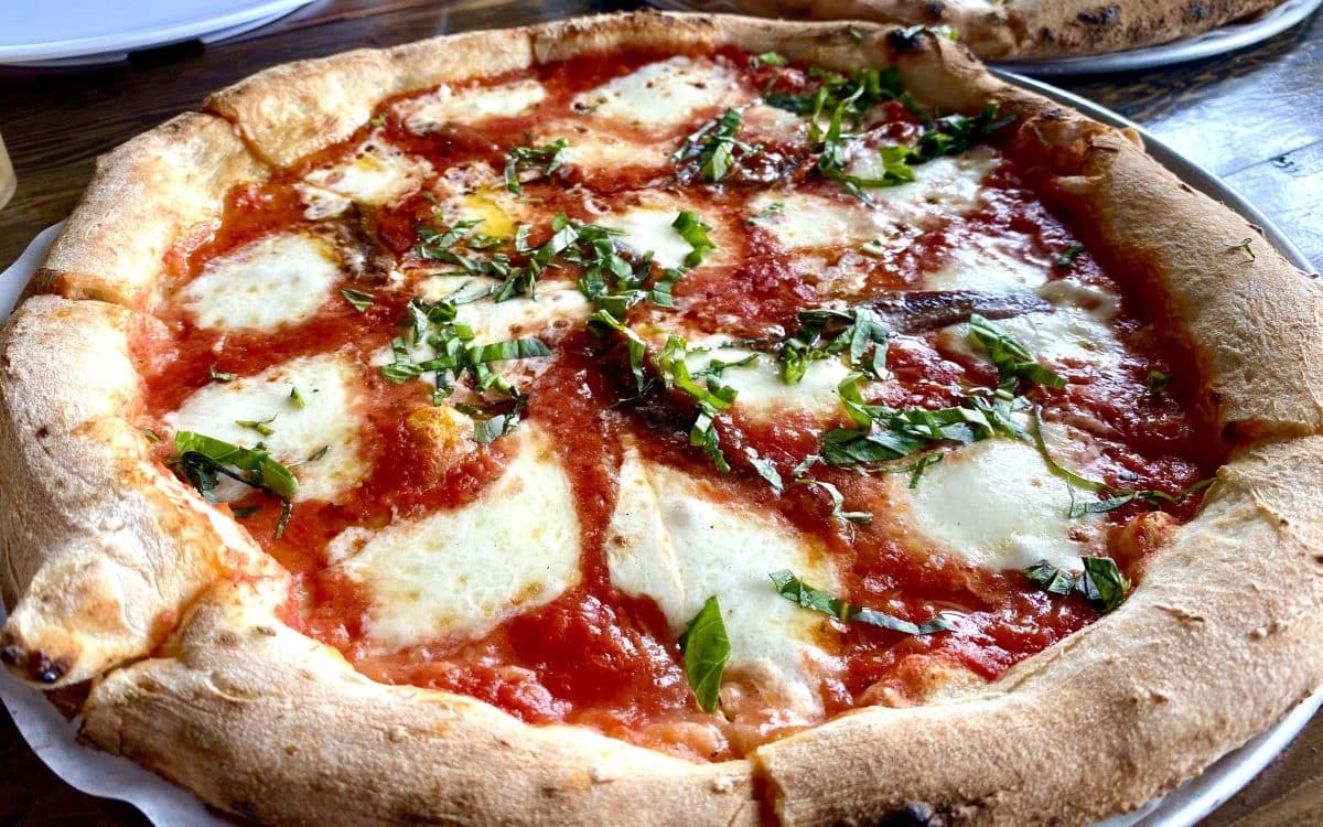 Wood-fired Neapolitan pizza on rustic table in a Rome pizzeria
